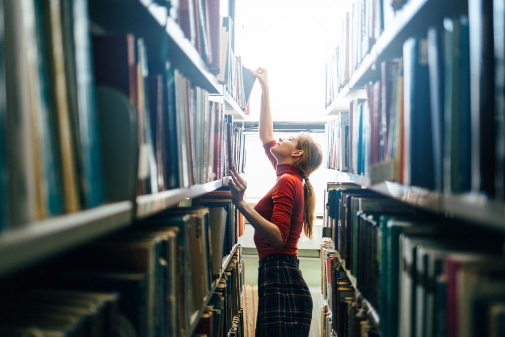 Une jeune femme qui cherche des livres dans une bibliothèque 
