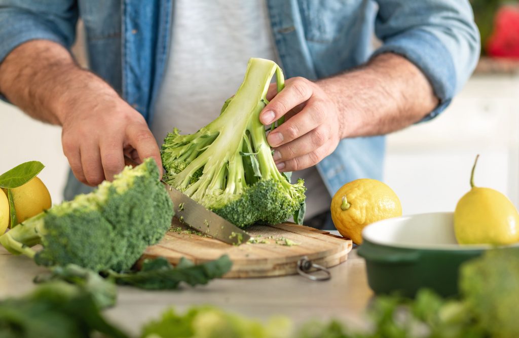 Personne coupant des légumes frais pour illustrer une consommation saine et durable