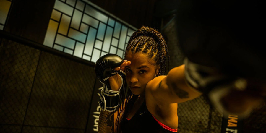 Une championne de MMA en position de combat, gants aux mains.