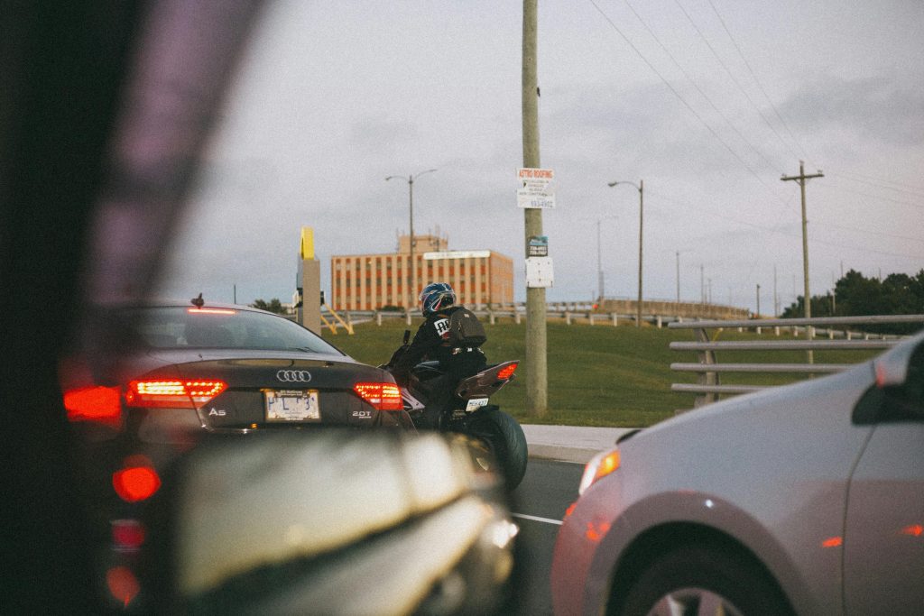 Un motard circulant pres d’une voiture dans la rue